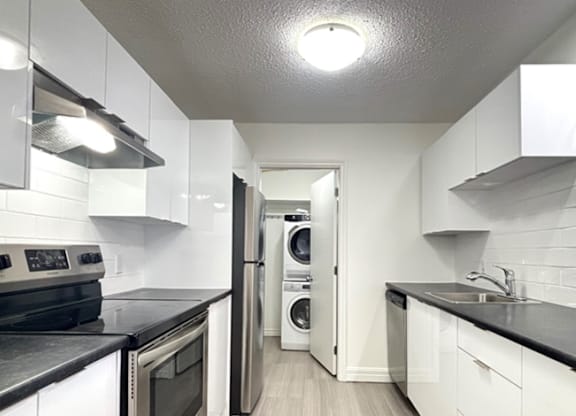 A kitchen with white cabinets and black countertops.