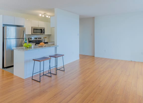 A kitchen with a refrigerator, stove, and bar stools.