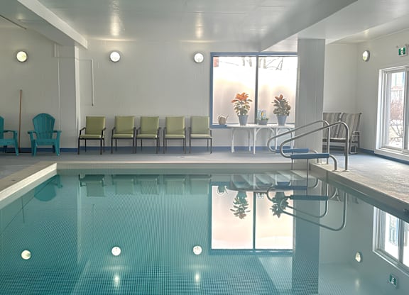 A large indoor swimming pool with a row of chairs and a staircase.