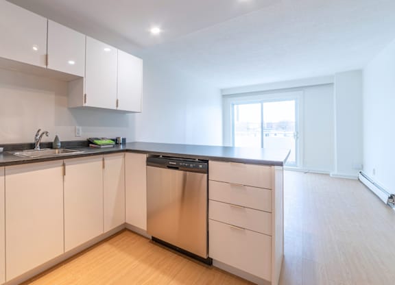 A kitchen with white cabinets and a black dishwasher.