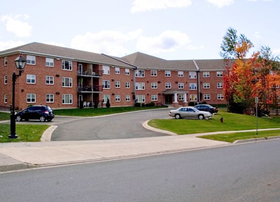A large red brick building with a parking lot in front.