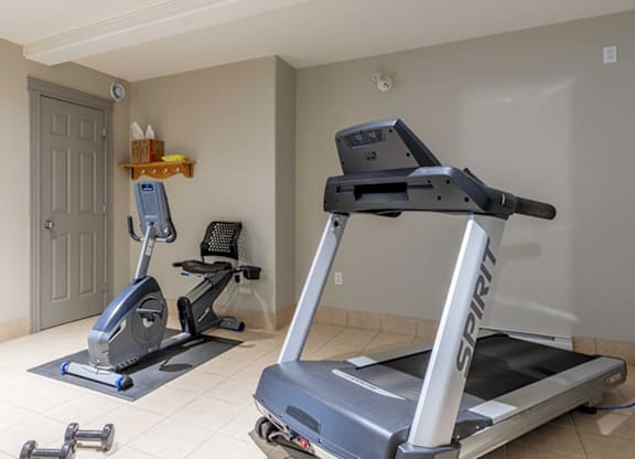 A Spinning bike and a treadmill in a room.