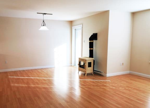 A room with wooden flooring and a wood-burning stove.