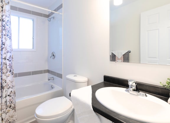 A white toilet sits next to a bathtub in a bathroom.
