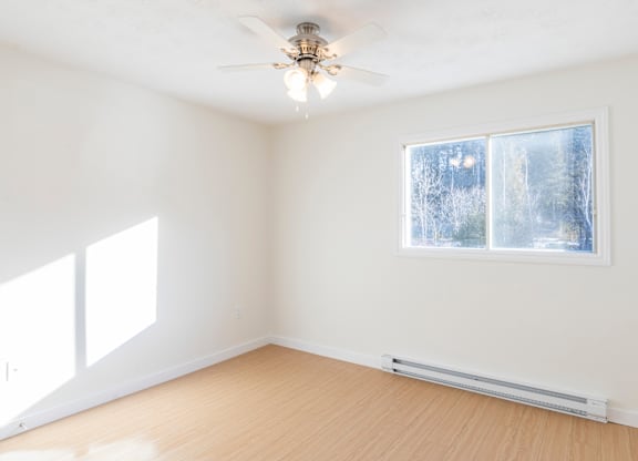 A room with a ceiling fan and a window showing a snowy scene outside.