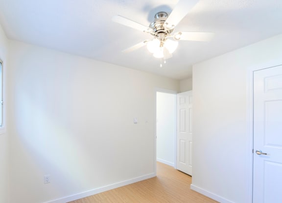 A room with a ceiling fan and two doors.