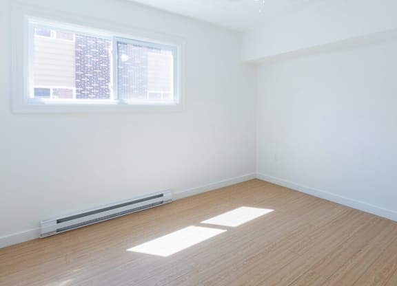 A room with a window and a radiator on the floor.