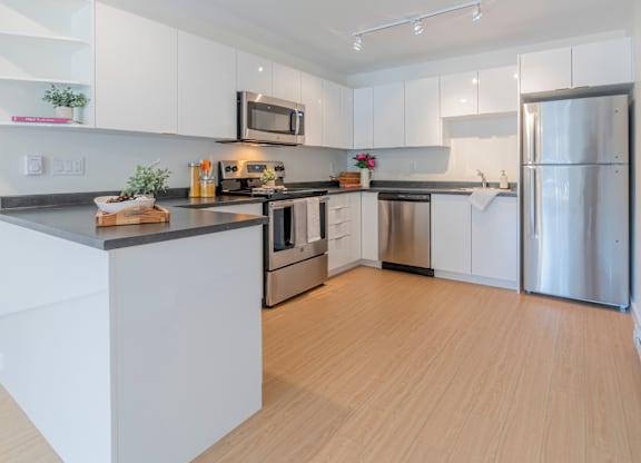 A modern kitchen with white cabinets and stainless steel appliances.