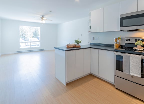 A modern kitchen with white cabinets and a wooden floor.
