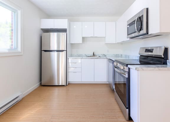 A kitchen with white cabinets and a stainless steel refrigerator.