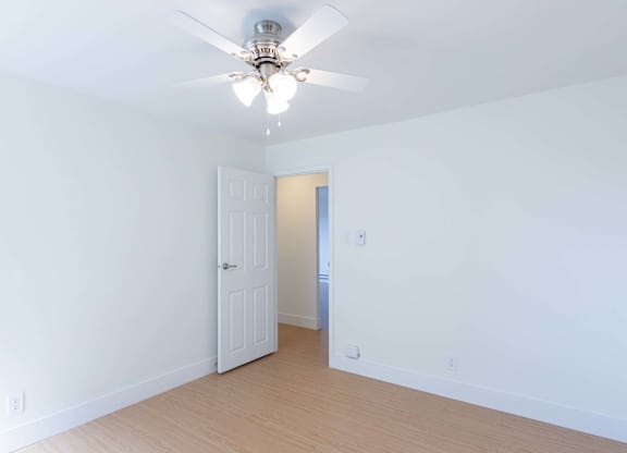 A room with a ceiling fan and a door.