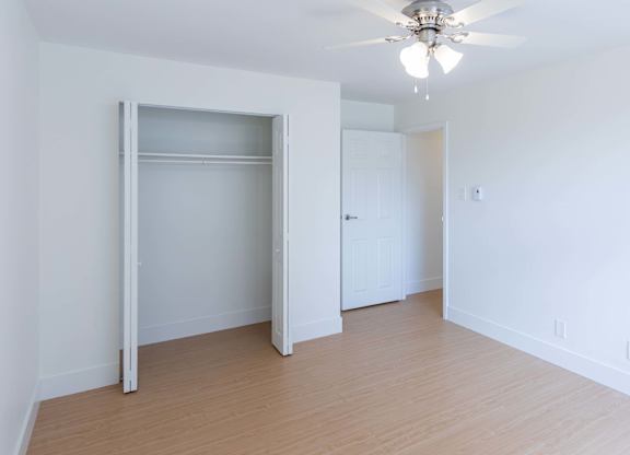 A room with a ceiling fan and a large open door.