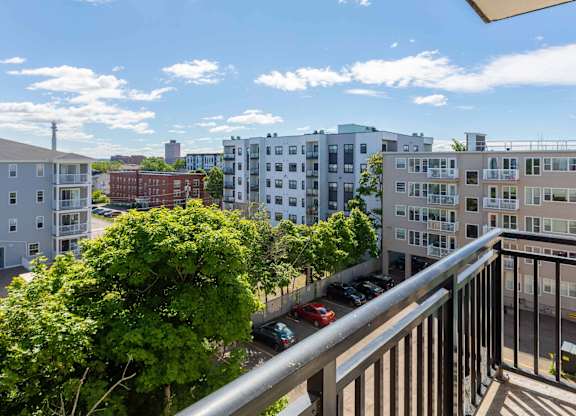 A balcony overlooks a parking lot and buildings.