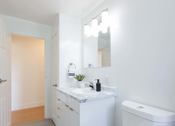 A white bathroom with a toilet, sink, and mirror.