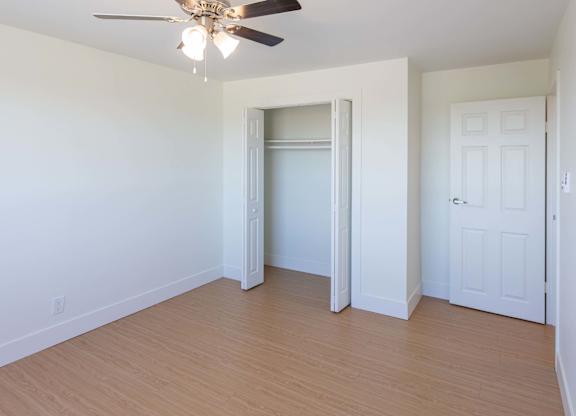 A room with a ceiling fan and a doorway leading to another room.
