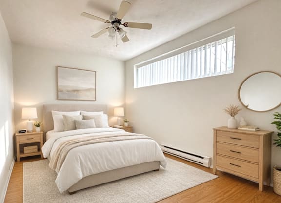A bedroom with a large bed, a ceiling fan, and a nightstand with a lamp.