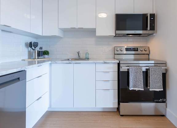 A modern kitchen with white cabinets and appliances.