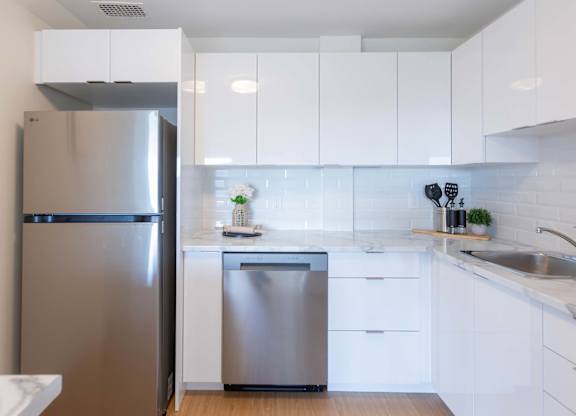A modern kitchen with a stainless steel refrigerator and dishwasher.