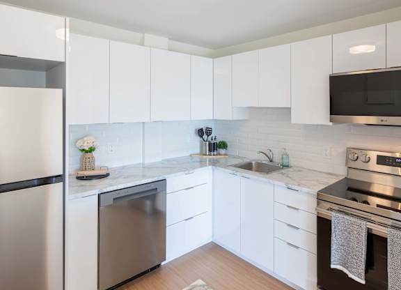 A modern kitchen with white cabinets and stainless steel appliances.