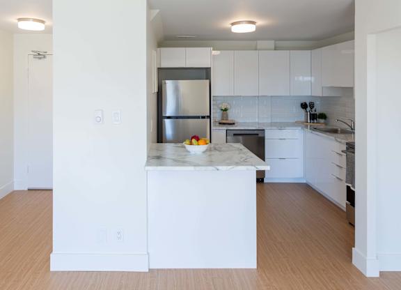 A kitchen with white cabinets and a marble island.