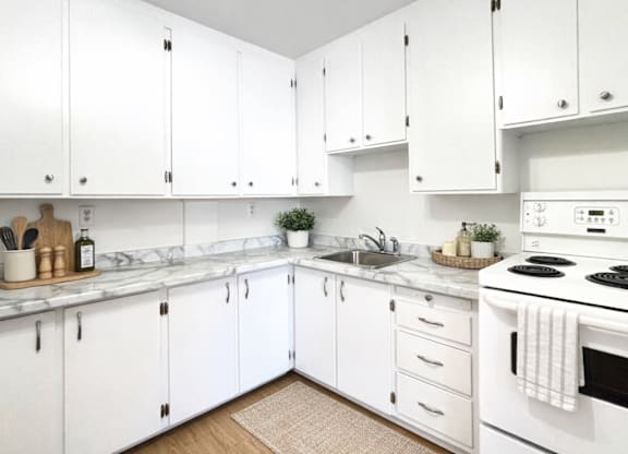 A kitchen with white cabinets and a white stove top oven.