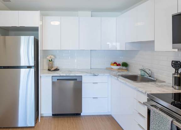 A modern kitchen with white cabinets and stainless steel appliances.