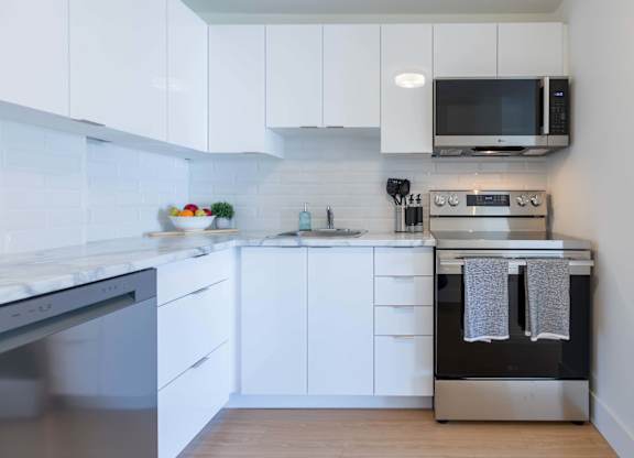 A modern kitchen with white cabinets and stainless steel appliances.