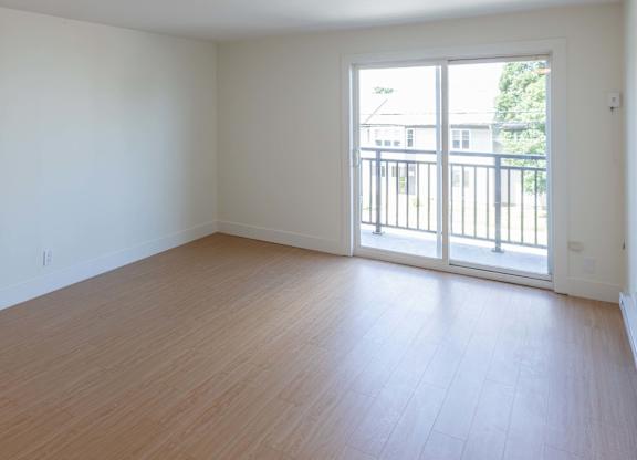 A room with wooden flooring and a sliding glass door.