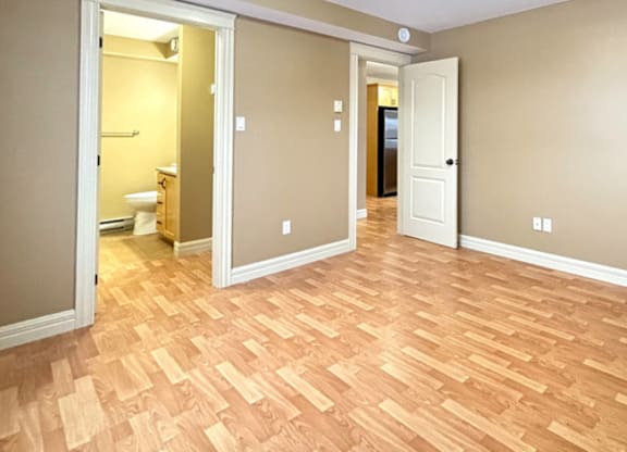 A room with wooden flooring and two doors.