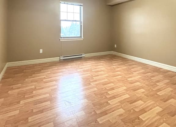 A room with wooden flooring and a window.