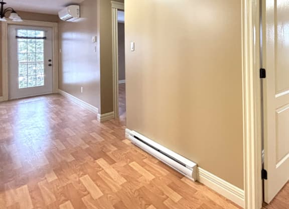 A room with a wooden floor and a wall-mounted air conditioner.