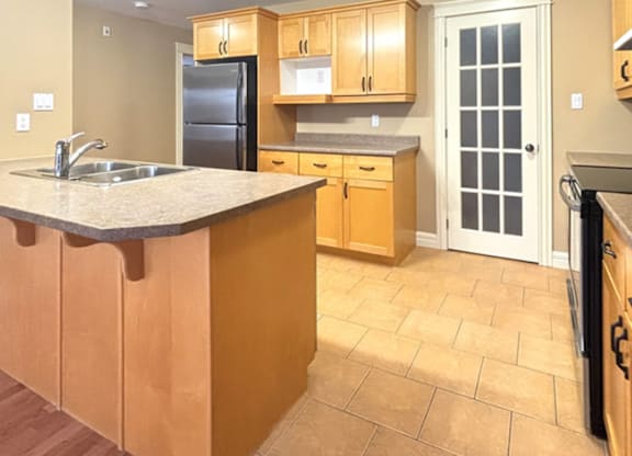 A kitchen with wooden cabinets and a black refrigerator.