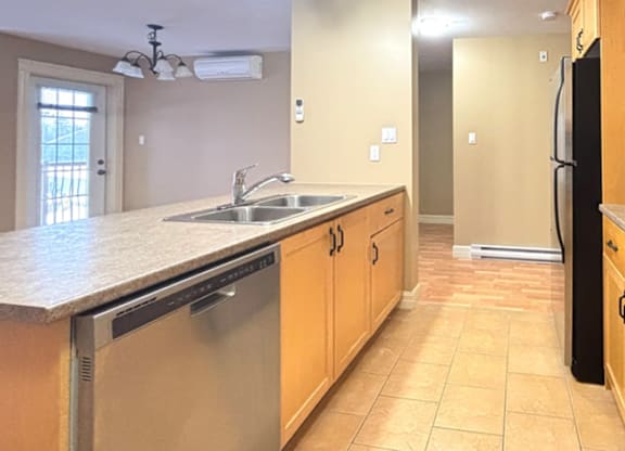A kitchen with a stainless steel dishwasher and black refrigerator.