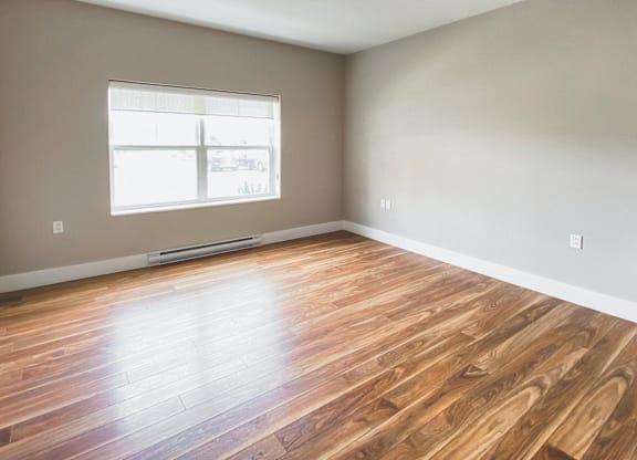 A room with wooden flooring and a window.
