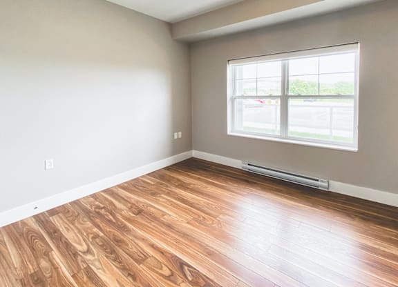 A room with a window and wooden flooring.