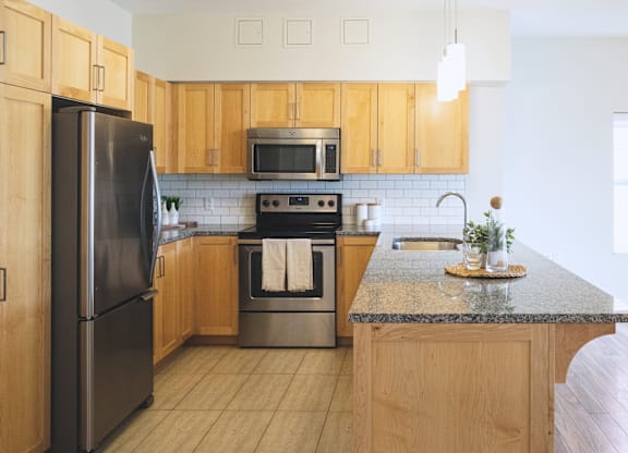 A kitchen with wooden cabinets and a black refrigerator.