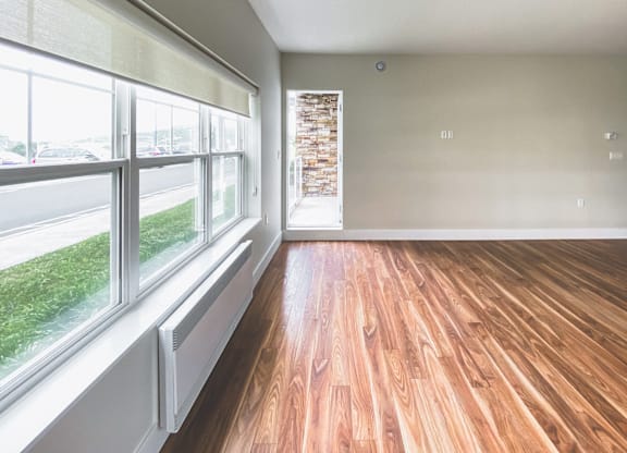 A room with wooden floors and a window overlooking a street.