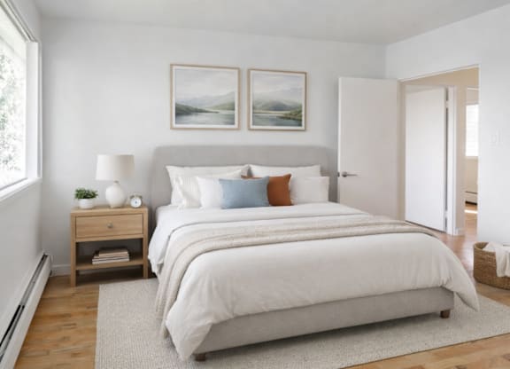 A bedroom with a large bed and two pictures on the wall.