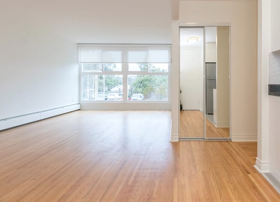 A room with wooden floors and a sliding glass door leading to a balcony.