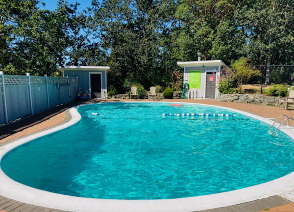A small pool with a white border and a white building in the background.