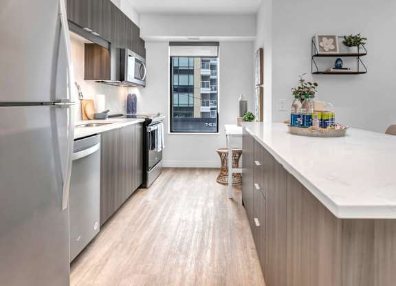 A modern kitchen with a white countertop and stainless steel appliances.
