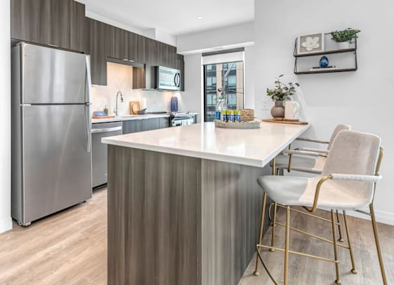 A modern kitchen with a stainless steel refrigerator and a white countertop.