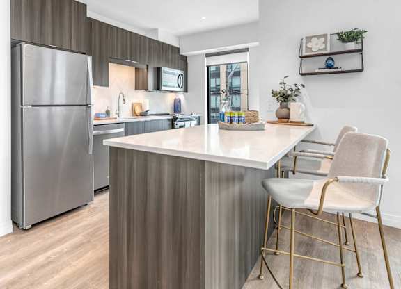 A modern kitchen with a stainless steel refrigerator and a white countertop.