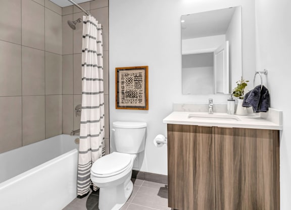 A bathroom with a white toilet, a wooden cabinet, and a shower curtain.