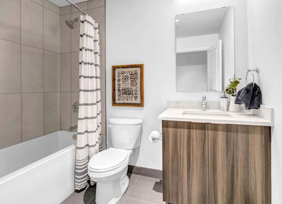 A bathroom with a white toilet, a wooden cabinet, and a framed picture on the wall.