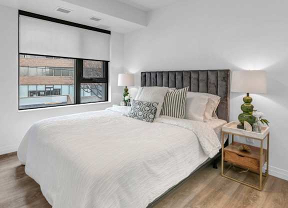 A bedroom with a large bed and a window with blinds.