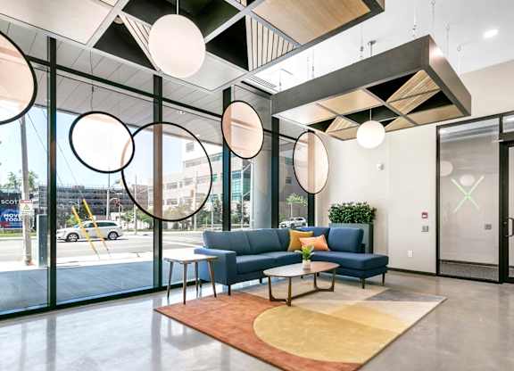A modern office lobby with a blue sofa and a wooden coffee table.