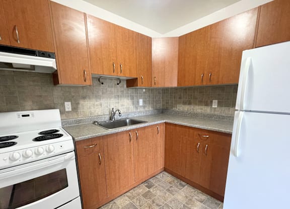 A kitchen with white appliances and wooden cabinets.