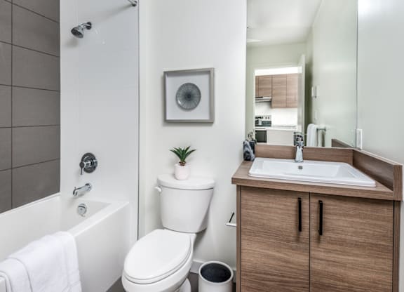 A bathroom with a toilet, sink, and mirror.