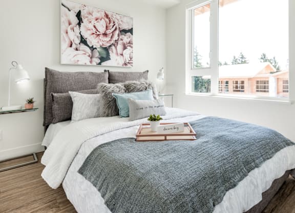 A bedroom with a large bed and a floral painting on the wall.